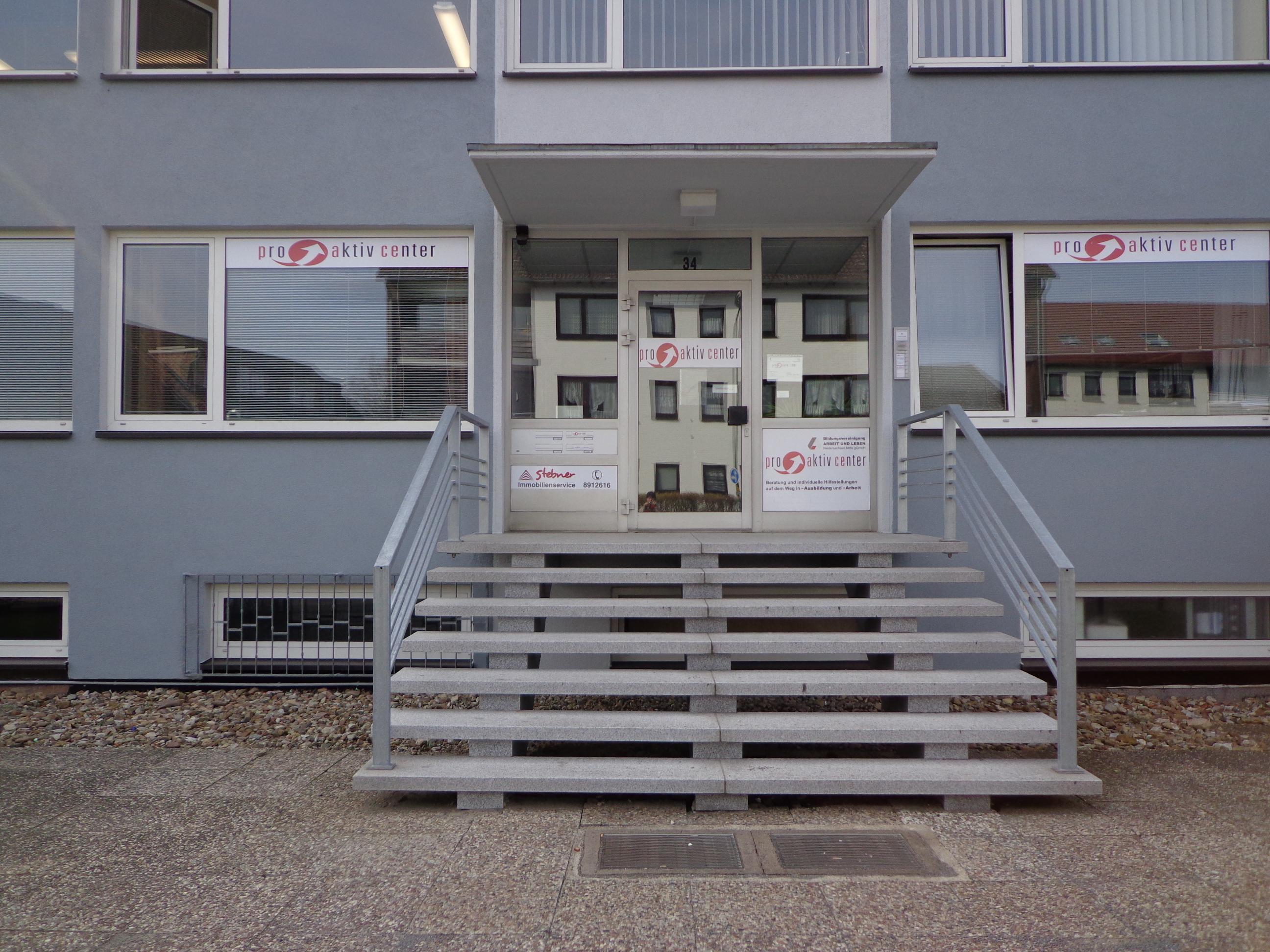 Der Haupteingang an der Wunstorfer Straße, an der Hauswand sind Schilder von Stebner Immobilien und dem Pro Aktiv Center